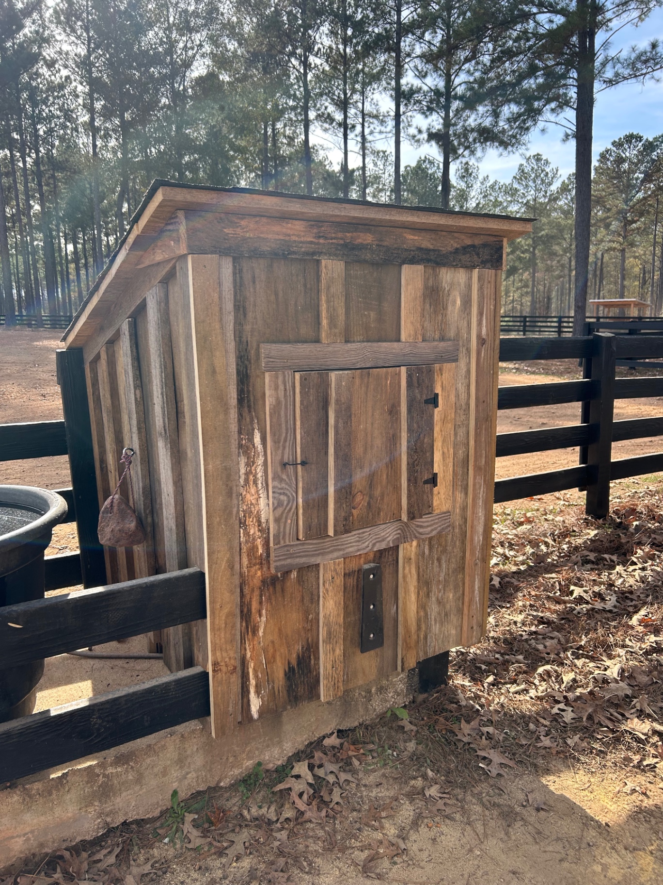 Custom wood fence enclosure with a hinged access door and sloped roof