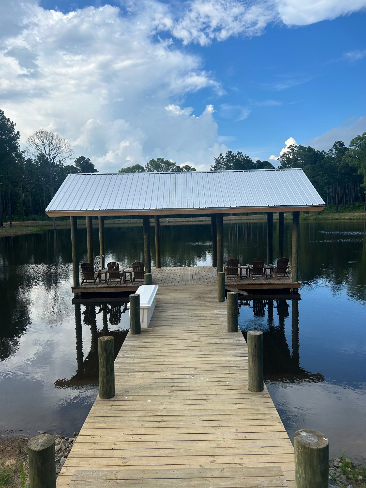 Custom covered lakeside dock with metal roof and Adirondack seating