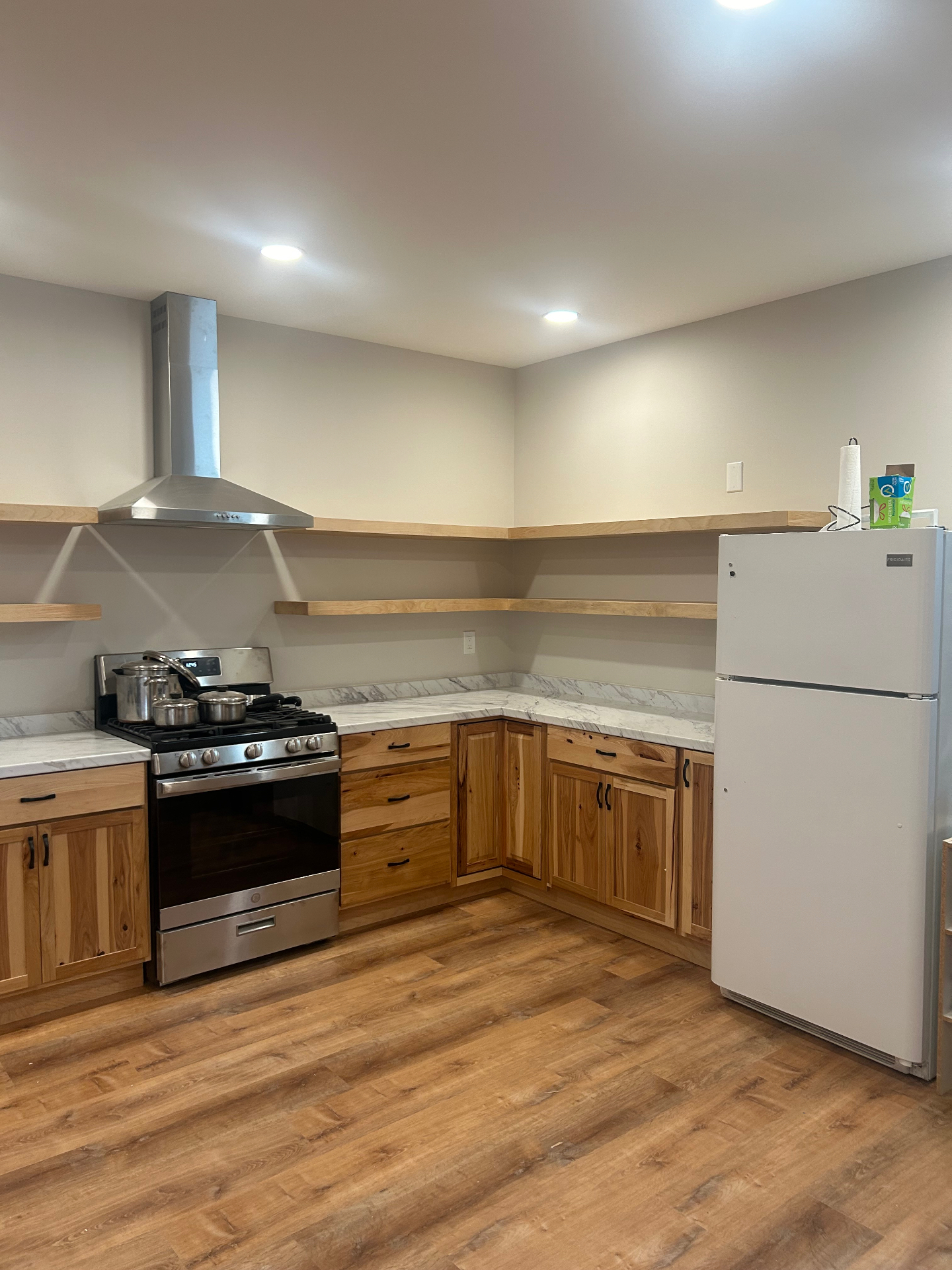 Renovated kitchen with stainless gas range, vent hood, and natural hickory cabinetry