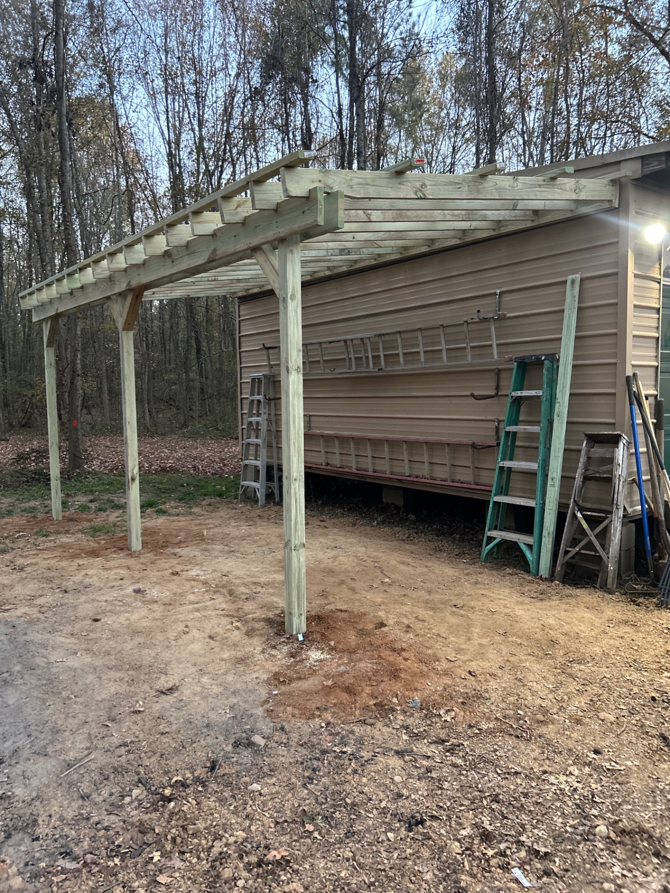 New lean-to roof framing with posts and rafters built alongside an exterior wall